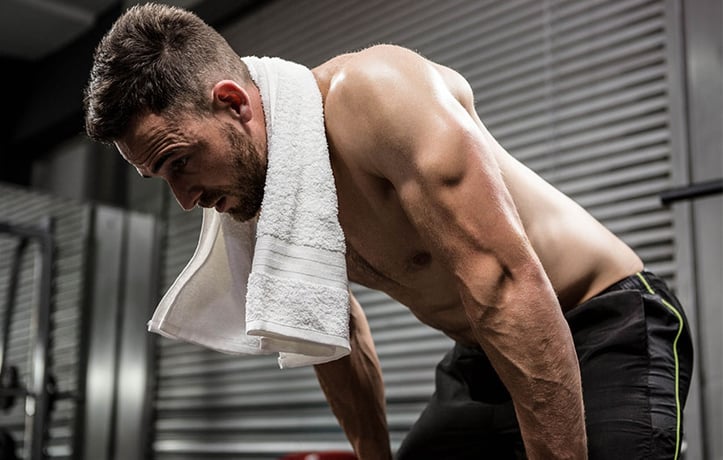 Male resting in gym with towel around neck