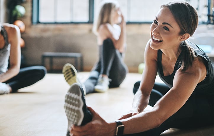 a smiling woman doing dynamic stretches