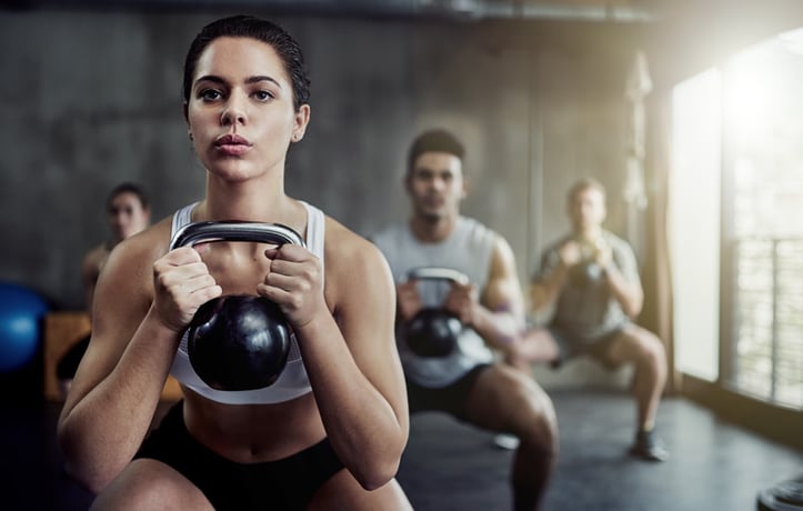 Women and men doing squats in a gym